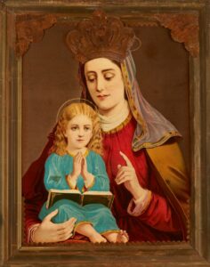 Obraz przedstawia kobietę - św. Annę – w czerwonej sukni, niebieskim welonie i koronie. Sylwetka ukazana od pasa w górę. Przed nią siedzi dziewczynka w niebieskiej sukience, z książką na kolanach, dłonie złożone do modlitwy, nad głową aureola, jasne loki.
