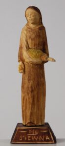 Rzeźba przedstawiająca stojącą kobietę w długiej sukni, z płachtą przewieszoną przez prawe ramię. W płachcie i w prawej dłoni ziarna zboża. Pod stopami postument z napisem „MB Siewna”. Rzeźba w różnych odcieniach brązu, zboże pomalowane na żółto.