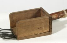 Przyrząd w kształcie małej drewnianej skrzyneczki z rączką i metalowymi zębami