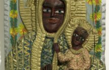 15. Fotografia płaskorzeźby z wizerunkiem Matki Boskiej z Dzieciątkiem, w tle kwiaty.