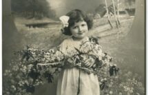 Czarno-biała pocztówka – dziewczynka z kwiatami, w tle pejzaż z brzozami, napis w języku niemieckim - życzenia z okazji Zielonych Świąt