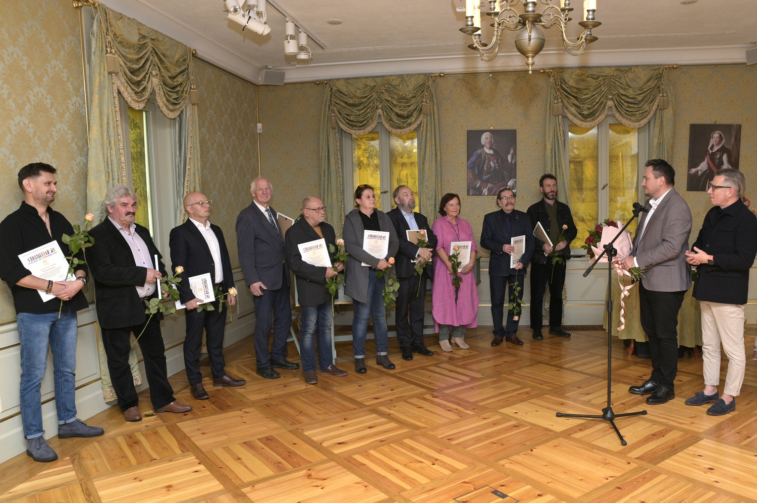 Ludzie w pałacowym wnętrzu z dyplomami i kwiaatami