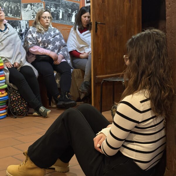 Otulone kocami kobiety odpoczywają siedząc na wystawie