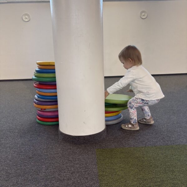 Mała dziewczynka sortuje kolorowe poduszki