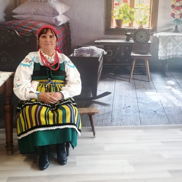 Kobieta w ludowym stroju w starej chałupie w skansenie