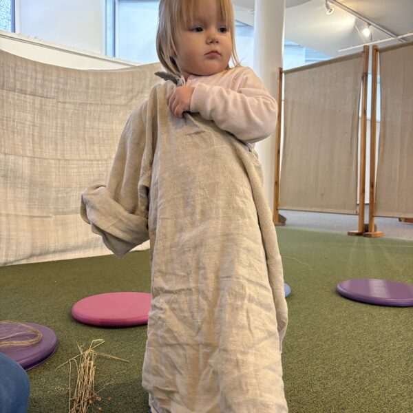 Dziewczynka zakłada lnianą koszulę. 