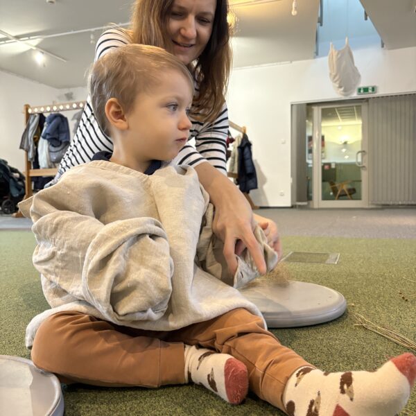 Kobieta nakłada na chłopca lnianą koszulę. 