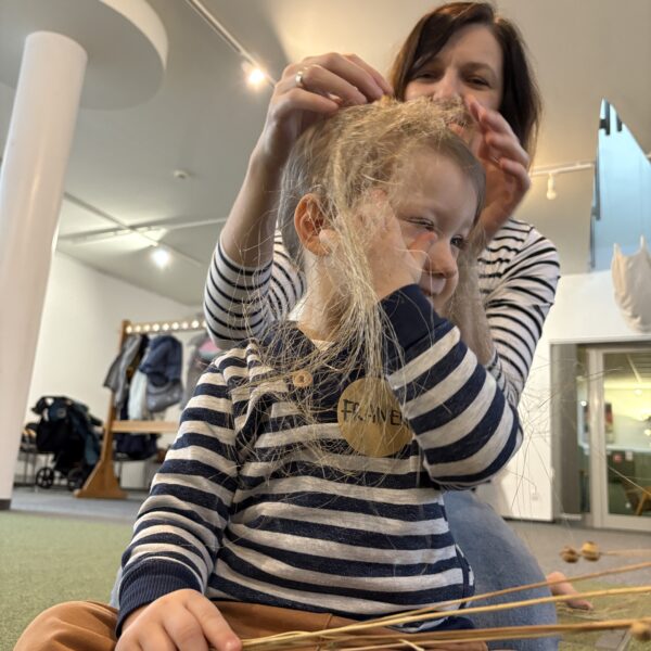 Kobieta nakłada chłopcu na głowę włókna lnu. 