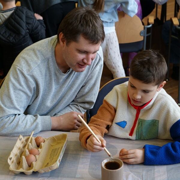 Mężczyzna obserwuje, jak chłopiec zdobi jajko metodą batikową (przy pomocy wosku pszczelego) 