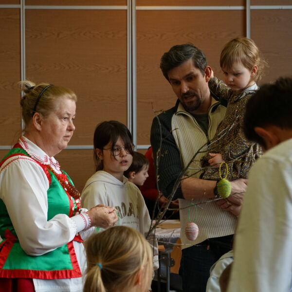 Kobieta w stroju kurpiowskim rozmawia z rodziną. 