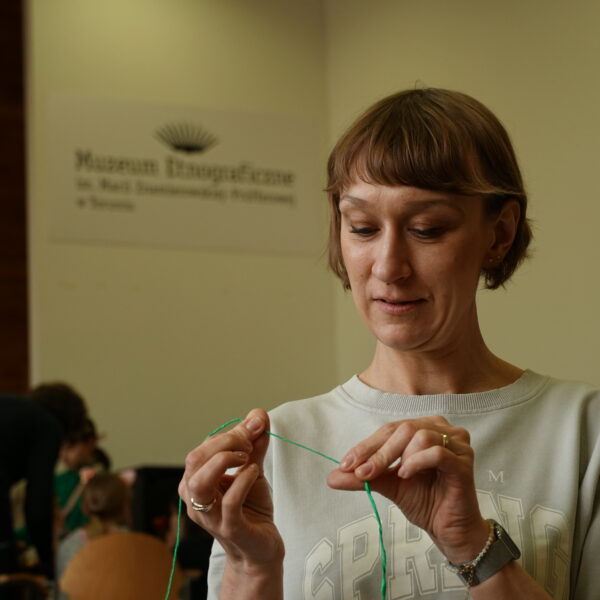 Kobieta trzyma w ręce nitkę. 