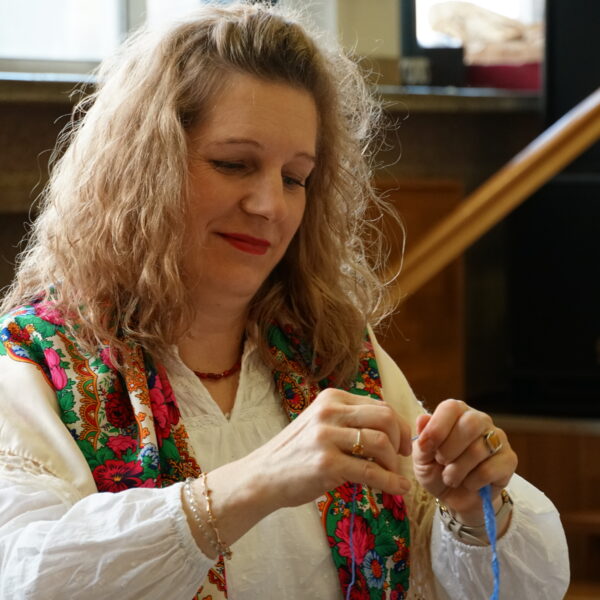 Kobieta w kręconych jasnych włosach przygotowuje wielkanocne ozdoby 