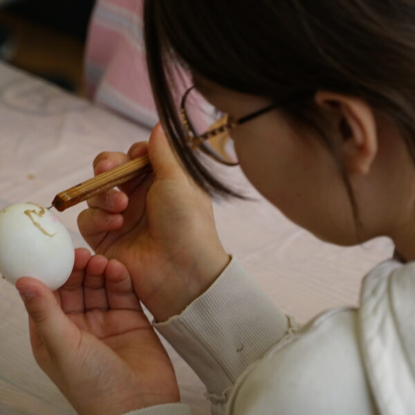 Dziewczynka zdobi jajko woskiem pszczelim 