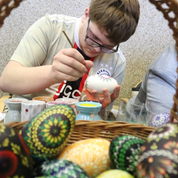 Kiermasz Wielkanocny - stoisko z pisankami, mężczyzna zdobi pisankę metodą batikową 