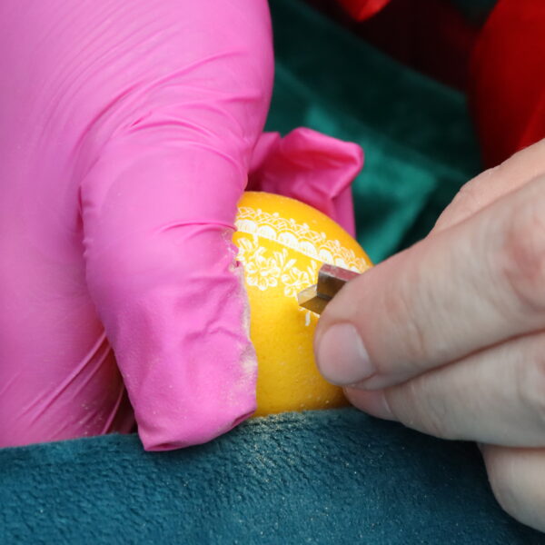 Dłonie trzymają pisankę - zdobienie 