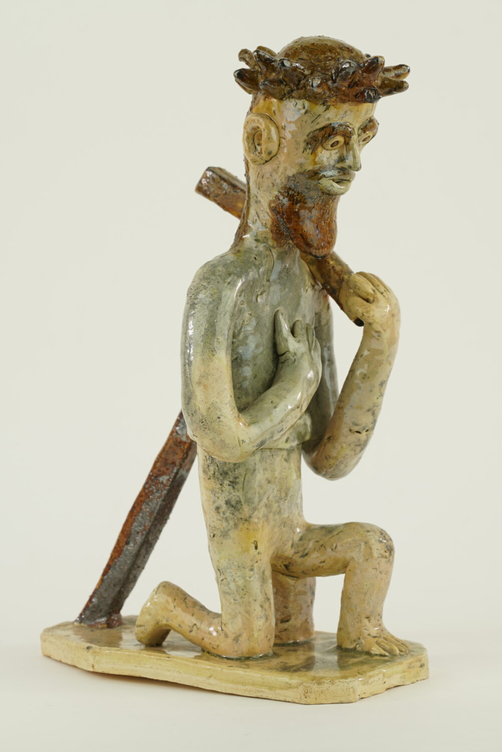 Chrystus klęczy na jedynm kolanie, na plecach ma krzyż - rzeźba