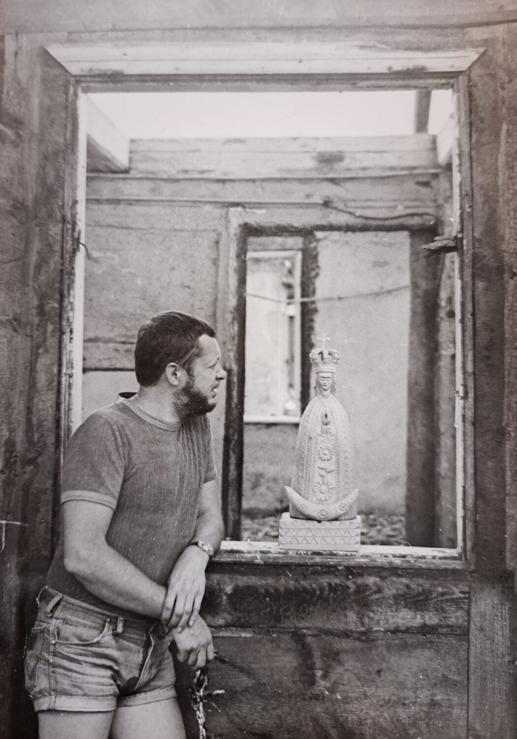 Mężczyzna stoi oparty o okno, w którym stoi figura Matki Boskiej Skępskiej