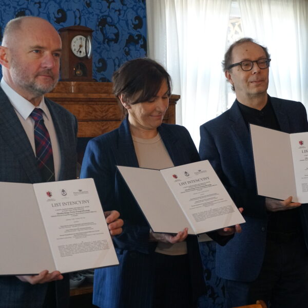 Dwóch mężczyzn, jedna kobieta trzymają otwarte teczki z dokumentem