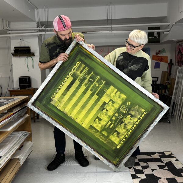 Mężczyzna i kobieta trzymają wielkoformatową pracę graficzną.