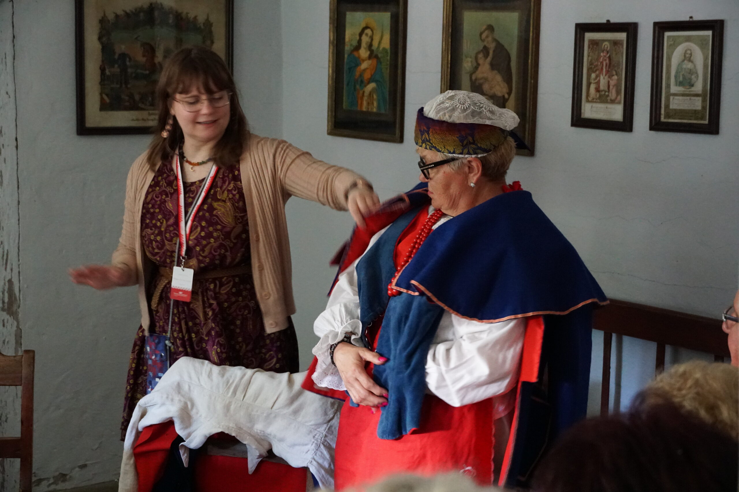 Kobieta przymierza strój kujawski - pomaga jej pracownica muzeum