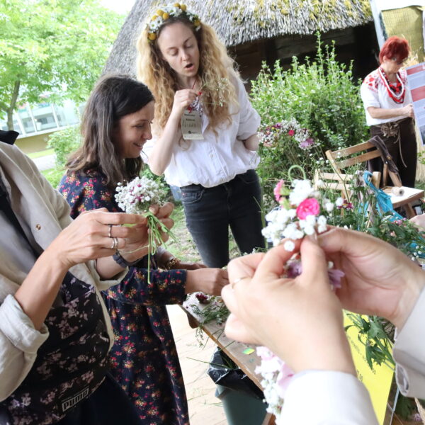 Kobiety zaplatają wianki z żywych kwiatów 