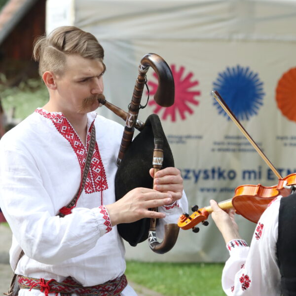 Mężczyźni w strojach ludowych grają na instrumentach 